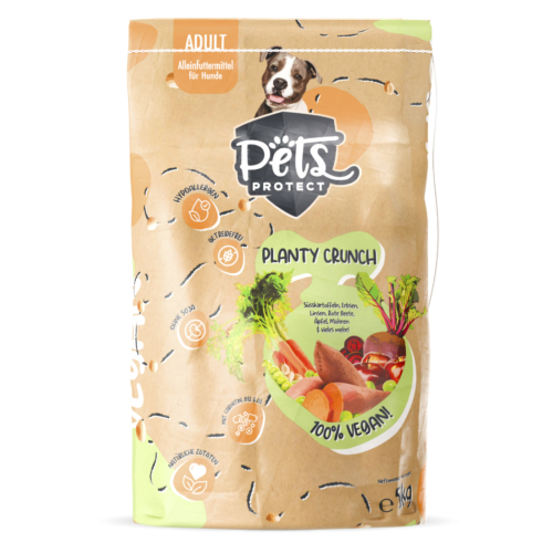 Verpackung des veganen Trockenfutters Planty Crunch von Pets Protect in einem umweltfreundlichen braunen Papierbeutel mit grünen und orangefarbenen Akzenten für eine natürliche Optik. Die Verpackung zeigt frische Gemüse-Illustrationen sowie Hinweise auf die 100% vegane, getreidefreie und hypoallergene Rezeptur – ideal für allergische Hunde. Oben in der Mitte der Verpackung ist ein süßer grau-weißer American Staffordshire Terrier abgebildet, der freundlich schaut.